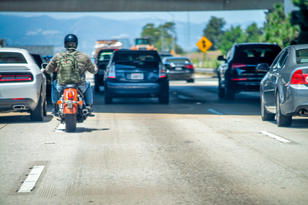 A motorcycle lane splitting while on the freeway.