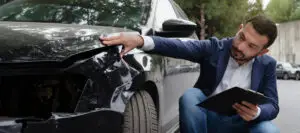 A man is inspecting a vehicle that just got into a fender bender.
