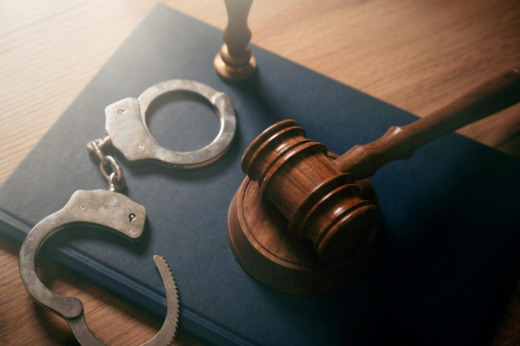 A gavel with a pair of handcuffs on top of a desk.