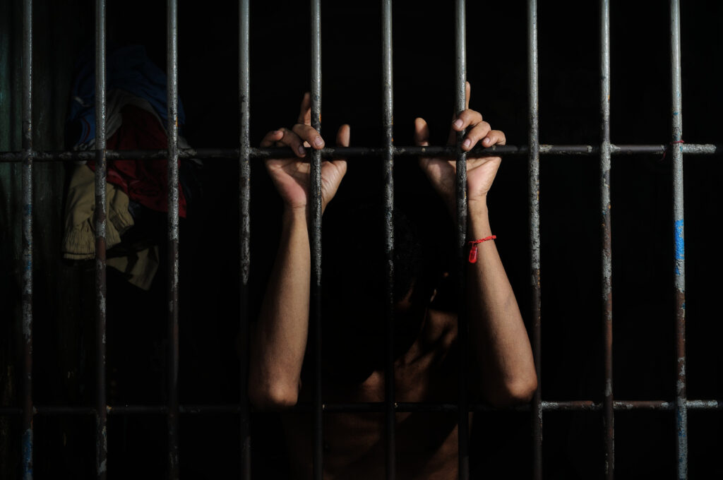 Someone arrested and sitting in a jail cell.
