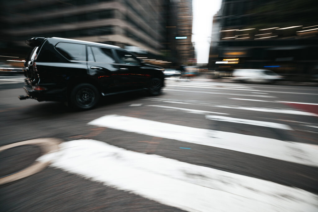 Black car turning right onto marked cross-walk